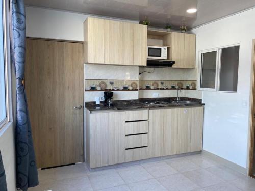 a kitchen with wooden cabinets and a microwave at Edificio Pacifica Aptos in Cali