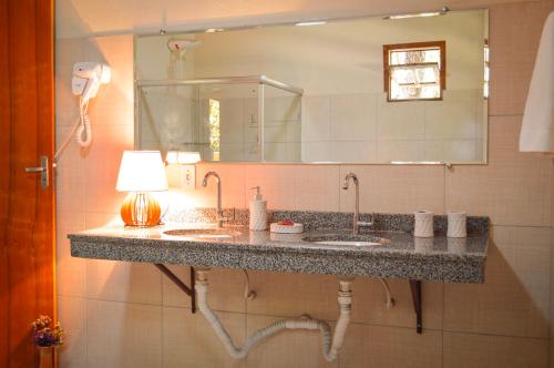 a bathroom with two sinks and a large mirror at Villaflor Pousada in Vale do Capao