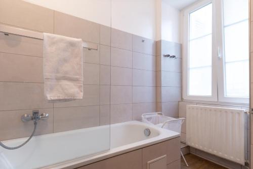 La salle de bains est pourvue d'une baignoire et d'une fenêtre. dans l'établissement Travel Homes - Le Carls: agréable, mignon, moderne, à Mulhouse