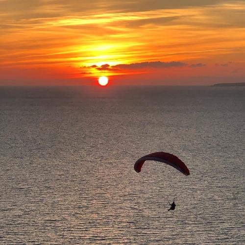 a person kite surfing in the ocean at sunset at Red House Bed & breakfast in Llucmajor