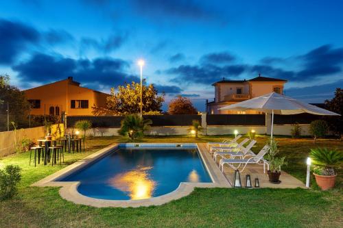 a backyard with a swimming pool with chairs and an umbrella at Red House Bed & breakfast in Llucmajor