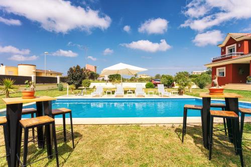 a pool with two tables and chairs next to a house at Red House Bed & breakfast in Llucmajor