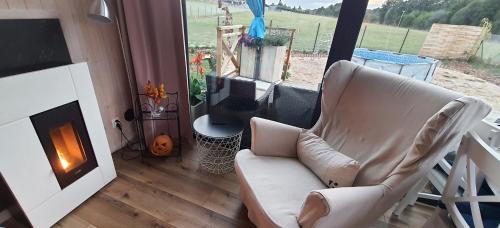 a living room with a chair and a fireplace at Domek mazurski całoroczny nad jeziorem z Sauną fińską I Jacuzzi SPA in Pasym