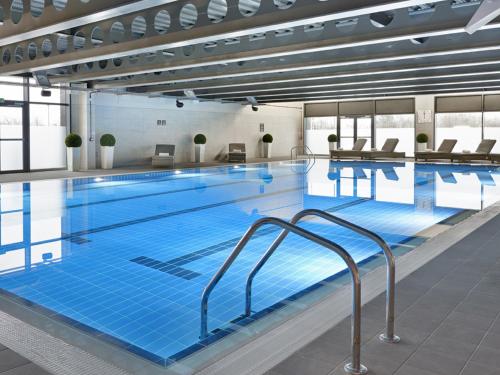 a large swimming pool with blue tiles in a building at Village Hotel Aberdeen in Aberdeen