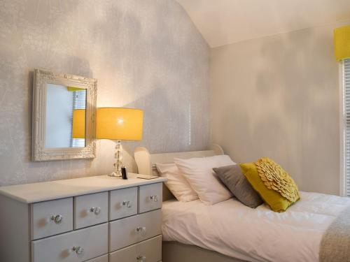 Dormitorio con cama con espejo y tocador en Clickers Cottage, en Woodford