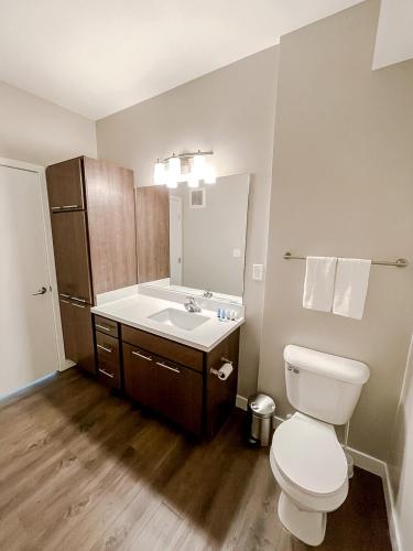 a bathroom with a white toilet and a sink at Sleepover Premier Downtown Des Moines Apartments in Des Moines