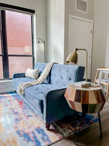 a blue couch in a living room with a table at Sleepover Premier Downtown Des Moines Apartments in Des Moines