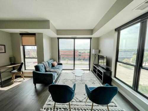 a living room with a couch and chairs and windows at Sleepover Premier Downtown Des Moines Apartments in Des Moines