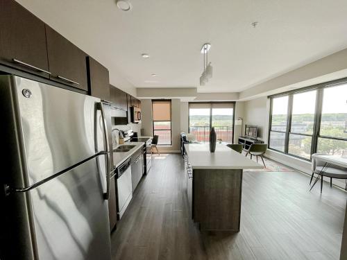a kitchen with a refrigerator and a table with chairs at Sleepover Premier Downtown Des Moines Apartments in Des Moines