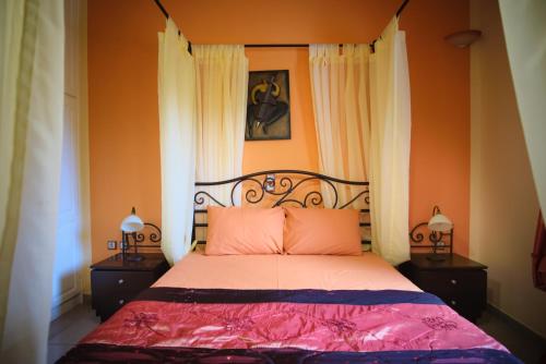 a bedroom with a bed with pink sheets and orange walls at Vretti's House in Kythira