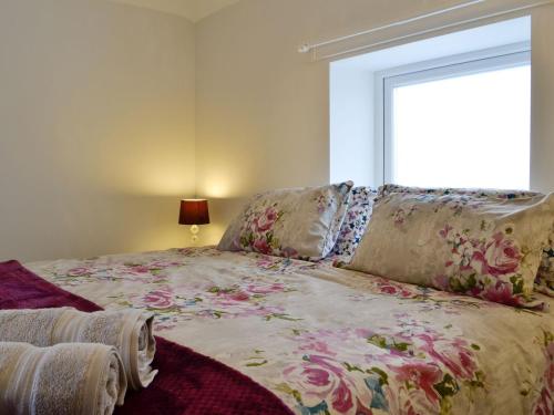 sypialnia z łóżkiem z kwiecistym kocem i oknem w obiekcie Cornel Clyd cosy Corner w mieście Cilcennin