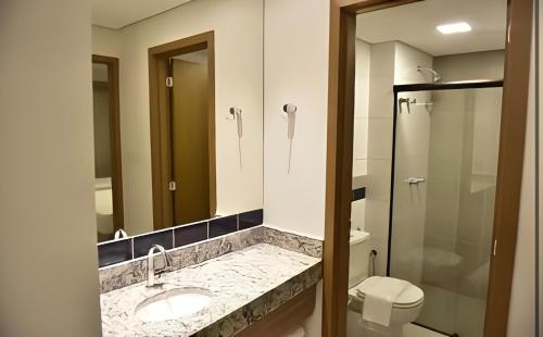 a bathroom with a sink and a toilet and a mirror at Prive Praias do Lago Eco Resort in Caldas Novas