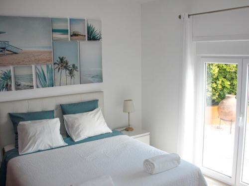 プライア・ダ・アレイア・ブランカにあるCasa Azulの白いベッドルーム(ベッド1台、窓付)