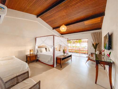 a large bedroom with a bed and a desk and a bed sidx sidx sidx sidx at Arraial Bangalô Praia Hotel in Arraial d'Ajuda