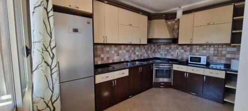 a kitchen with brown cabinets and a white refrigerator at Luis Penthouse in Berat