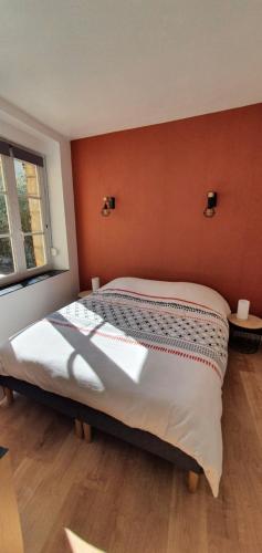 une chambre avec un grand lit avec un mur orange dans l'établissement Appartement d'Hippolyte - Vue musée Rimbaud, à Charleville-Mézières