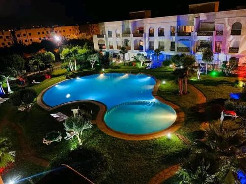una gran piscina frente a un edificio por la noche en Appartement avec piscine à saidia Climatisation et Wifi en Saïdia