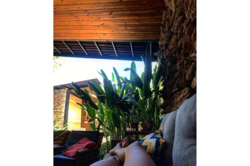 a person laying on a couch looking out a window at Casa jardim com ofurô - Chapada dos veadeiros in Cavalcante