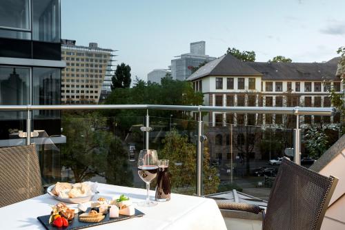 a table with a plate of food and a glass of wine at Villa Hotel Frankfurt by MZ HotelCollection in Frankfurt