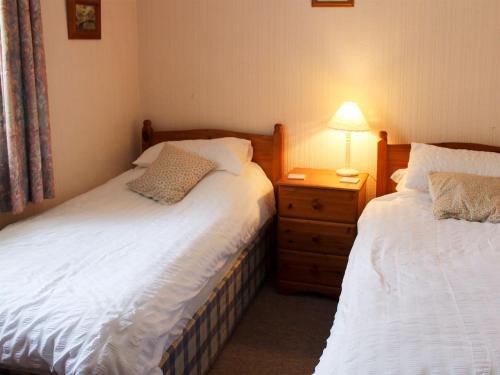 1 dormitorio con 2 camas y mesita de noche con lámpara en Caxton Nook, en Windermere