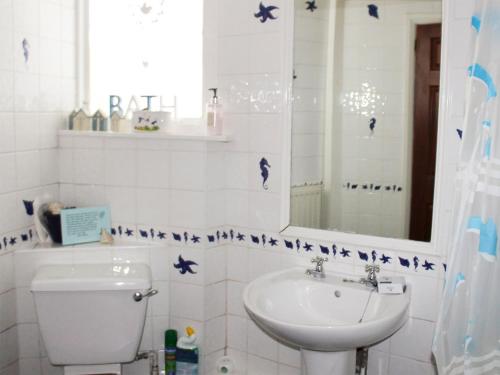y baño con lavabo, aseo y espejo. en Caxton Nook, en Windermere