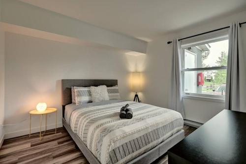 Un dormitorio blanco con una cama grande y una ventana en *Nouveauté* Foyer au bois, Plage, Montagne et + en Magog-Orford