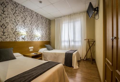 a hotel room with two beds and a window at Hotel Casa Jacinto Pamplona in Burlada