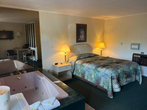 Habitación de hotel con cama y bañera en Gray Wolf Lodge en Manistique
