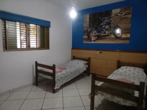 Zimmer mit 2 Betten und einem Motorrad an der Wand in der Unterkunft RECANTO DO ALVORADA in Dourados