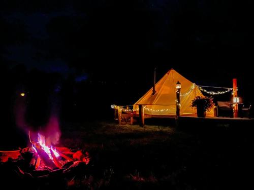 a tent with a fire in a field at night at Lux Glamping, Lammas 