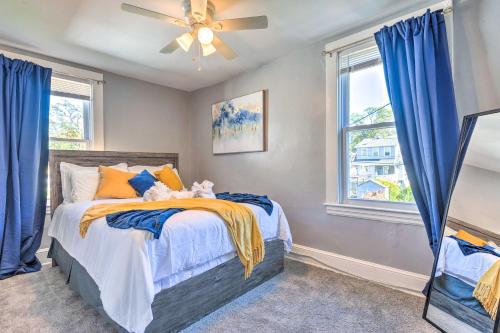 a bedroom with a bed with blue curtains and a ceiling fan at Charming Baltimore Home with Deck and Fire Pit! in Baltimore