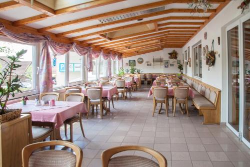 un restaurante con mesas y sillas rosas y ventanas en Gasthof Kessler, en Oberthulba