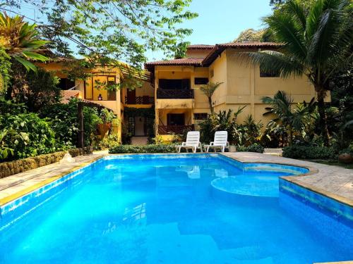 - une piscine avec 2 chaises en face d'une maison dans l'établissement Pousada Recanto dos Tangaras, à Juqueí