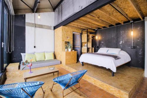 a bedroom with a bed and a couch and chairs at Santa Teresita Loft in Cali