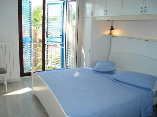 a white bed with blue pillows in a bedroom at Apartments Mare Losinjska 16 in Rabac