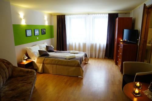 a bedroom with a bed and a couch and a television at Villa Goździk in Wisła