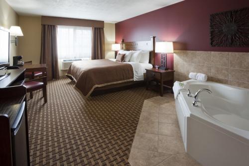 GrandStay Inn & Suites of Luverne في Luverne: غرفة في الفندق مع سرير وحوض استحمام