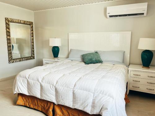 a bedroom with a large white bed and a mirror at Aruba Bliss Condos in Oranjestad