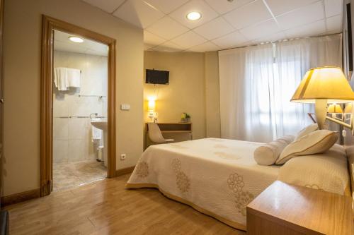 a bedroom with a bed and a bathroom with a shower at Hotel Casa Jacinto Pamplona in Burlada