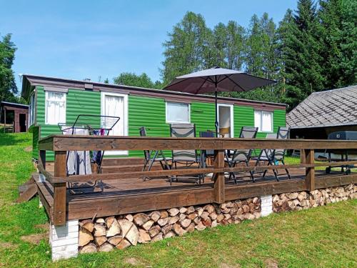 a house with a deck with chairs and an umbrella at Nad rybníkem Hnačov - rodinný rekreační areál 