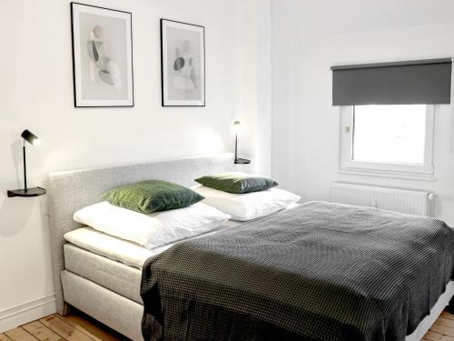 a white bedroom with a bed and two pillows at LIGHTPLACE • Design • Boxspring • Küche • Homeoffice •City nah in Braunschweig