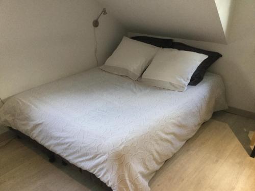 1 cama con sábanas blancas y almohadas en una habitación en Studio centre ville en Compiègne