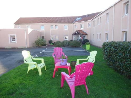 a group of chairs sitting on the grass in a yard at Hôtel Estuaire in Saint-Brevin-les-Pins