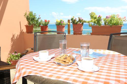 a table with a checkered table cloth with food on it at Akrogiali Hotel in Plomarion