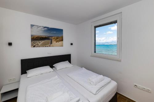 a white bedroom with a bed and a window at Golden Nin in Nin