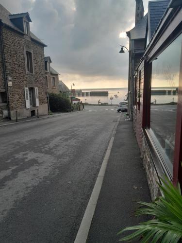 an empty street next to a building with the ocean in the background at Hotel La Voilerie Cancale bord de mer in Cancale