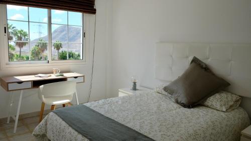a bedroom with a bed and a desk and a window at Atico Carlota- Feel Canarias ! in Chayofa