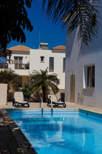 una piscina con 2 sillas y un edificio en Luxury Villa en Ayia Napa