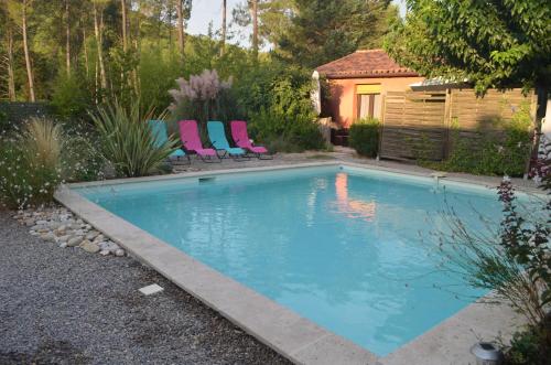 a swimming pool with chairs in a backyard at Gîte Les Esparrus in Villecroze