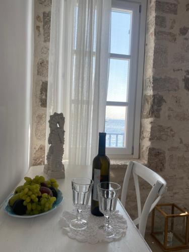 uma mesa com uma garrafa de vinho e um prato de uvas em Halki Sea Breeze - a waterfront villa em Halki
